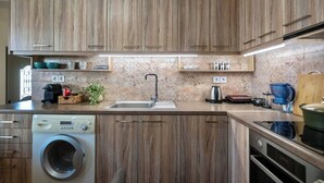 Een moderne keuken met houten kastjes, een ingebouwde wasmachine, een koffiezetapparaat en een waterkoker.