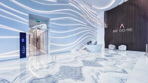 Eine moderne Hotellobby mit Marmorboden, einer Rezeption und einer Wand mit einem außergewöhnlichen Lichtdesign.