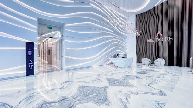 A modern hotel lobby with a marble floor, a reception desk, and a wall with a unique light design. - Elegant studio in Me Do Re Tower (Dubai)