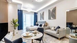 A modern hotel room with a bed, sofa, dining area, and a TV. - Elegant studio in Me Do Re Tower (Dubai)