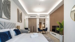 A modern hotel room with a large bed, a desk, and a TV. - Elegant studio in Me Do Re Tower (Dubai)