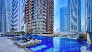 A modern high-rise building with a rooftop pool area, surrounded by other tall buildings. - Elegant studio in Me Do Re Tower (Dubai)