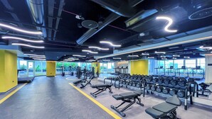 A spacious gym with various exercise equipment, large windows, and a modern design. - Elegant studio in Me Do Re Tower (Dubai)