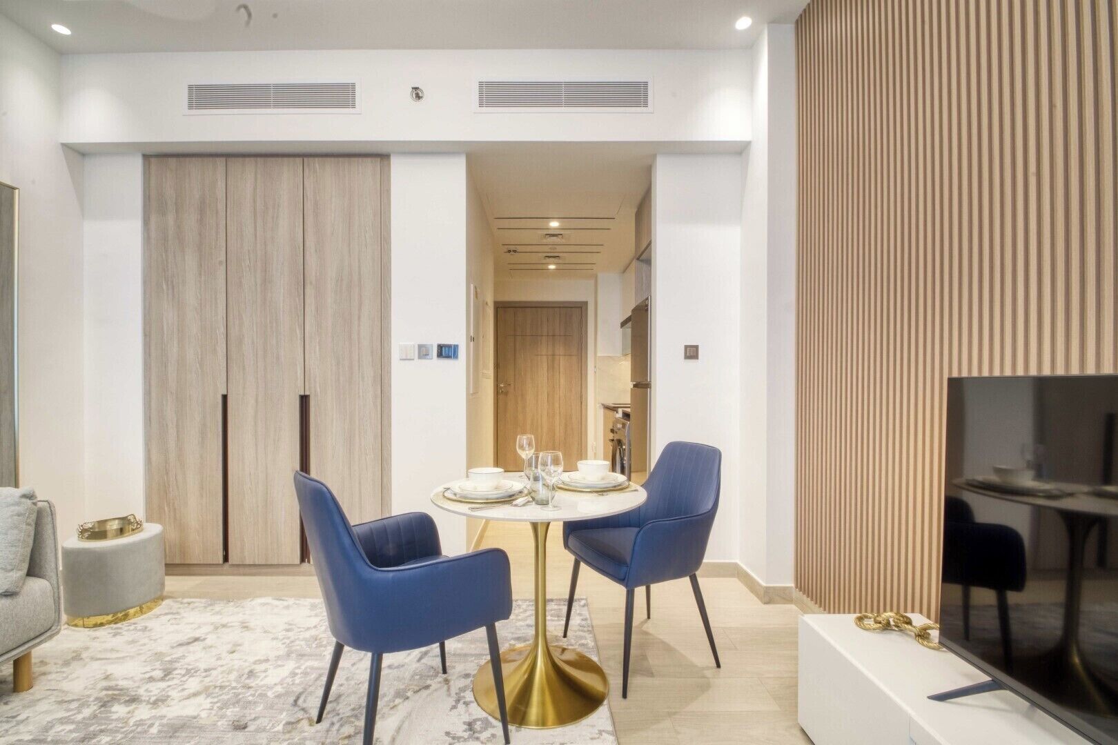 Un comedor moderno con una mesa redonda, dos sillas azules y una base dorada.