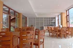 Un amplio comedor con mesas y sillas de madera, ventanas grandes y vistas al exterior.