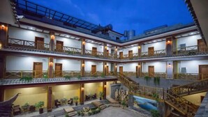A multi-story hotel with balconies, a central courtyard, and outdoor seating areas. - Lugu Manor Hotel (Ninglang)