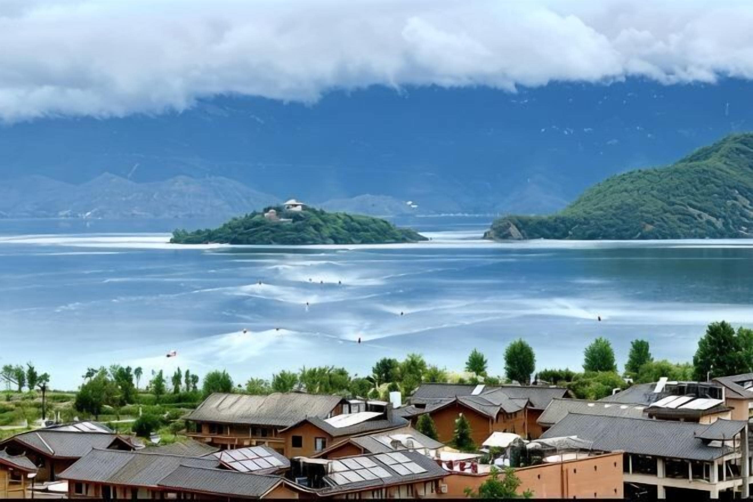 Blick auf einen See mit traditioneller Bebauung, einer kleinen Insel und Bergen im Hintergrund.