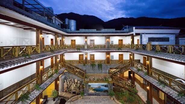 A courtyard with a central water feature, multiple balconies, and a stone pathway leading to a door. - Lugu Manor Hotel (Ninglang)