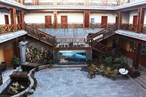 A courtyard with a central mural, stone steps, and seating areas. - Lugu Manor Hotel (Ninglang)