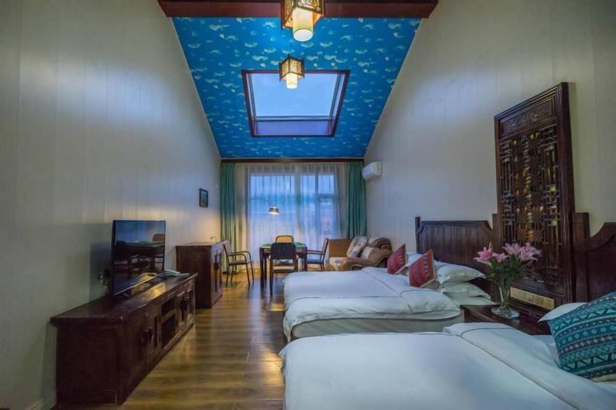 A hotel room with two beds, a TV, a desk, and a large window with a view.