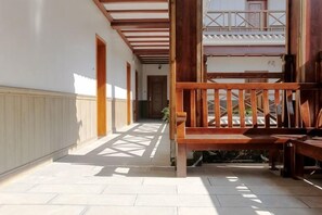 A covered corridor with wooden benches, a tiled floor, and a view of a building in the background. - Lugu Manor Hotel (Ninglang)