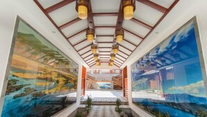 A corridor with glass walls, wooden ceiling beams, and hanging lights. - Lugu Manor Hotel (Ninglang)