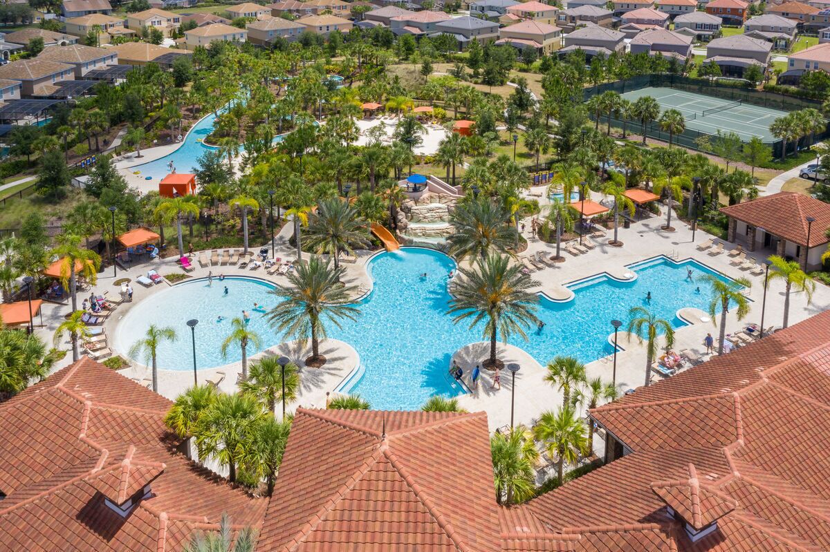 A resort with multiple swimming pools, palm trees, and a tennis court.