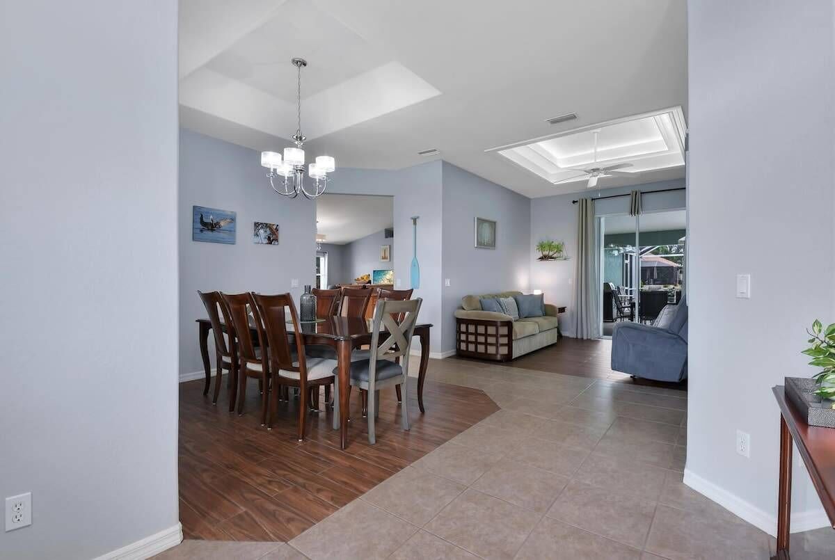 A spacious living area with a dining table and chairs, a sofa, and a ceiling fan.
