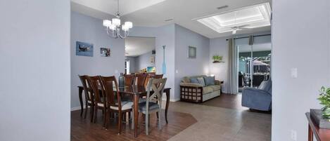 A spacious living area with a dining table and chairs, a sofa, and a ceiling fan.