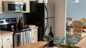 A modern kitchen with stainless steel appliances, a wooden countertop, and a dining area with wicker chairs. - Hidden Secret Waterfront Retreat (Cape Coral)