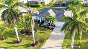 A residential area with a house, palm trees, and a well-maintained lawn. - Unwind in Paradise (Cape Coral)