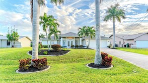 A residential area with multiple houses, well-maintained lawns, and palm trees. - Unwind in Paradise (Cape Coral)
