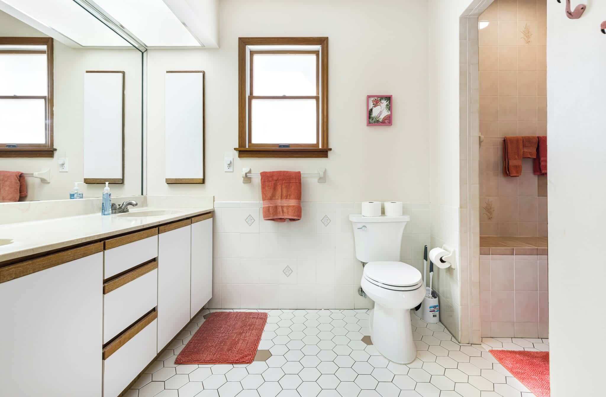 Un bagno con un lavandino bianco, mobili in legno, un water e uno spazio doccia.