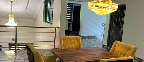 Un comedor con piso de mármol, una mesa de madera y sillas tapizadas en amarillo.