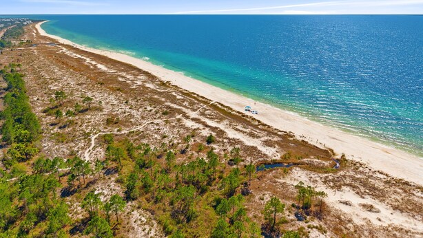 A coastal landscape with a sandy beach, clear blue waters, and sparse vegetation. - Spacious 4BR w/ Pool Access|Walk to Beach|Fire Pit (Port St. Joe)