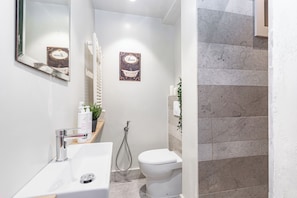 A modern bathroom with a white sink, a toilet, and a shower. There is a mirror above the sink and a decorative sign on the wall. - Loft Alma Rosa vicino a Piazza Vittorio by Wonderful Italy (Turin)