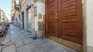 Una calle estrecha con coches aparcados y una gran puerta de madera a la derecha.