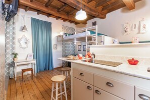 A kitchen with a wooden ceiling, a white countertop, a sink, and a window with blue curtains. - Loft Alma Rosa vicino a Piazza Vittorio by Wonderful Italy (Turin)