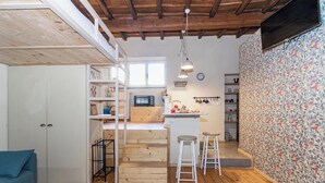 Una cocina acogedora con pisos de madera, armarios blancos y una pequeña isla con taburetes.