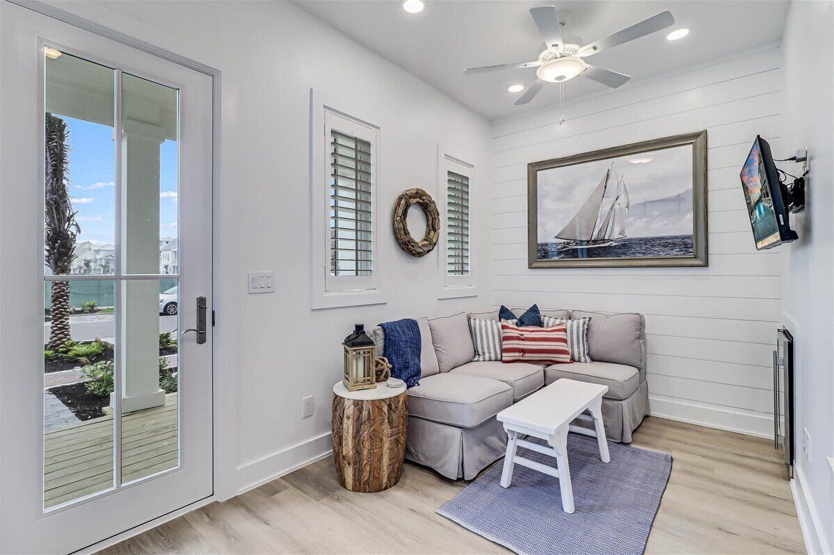 A living room with a beige sofa, a white coffee table, a side table with a lantern, and a framed picture of a sailboat.