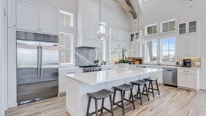 A spacious kitchen with a large island, stainless steel appliances, and a view of the city. - Summer Wind 217 TEA (Port Aransas)