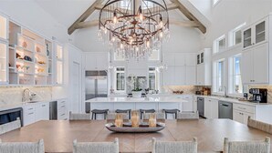 A spacious kitchen with a large island, white cabinetry, and a modern chandelier. - Summer Wind 217 TEA (Port Aransas)