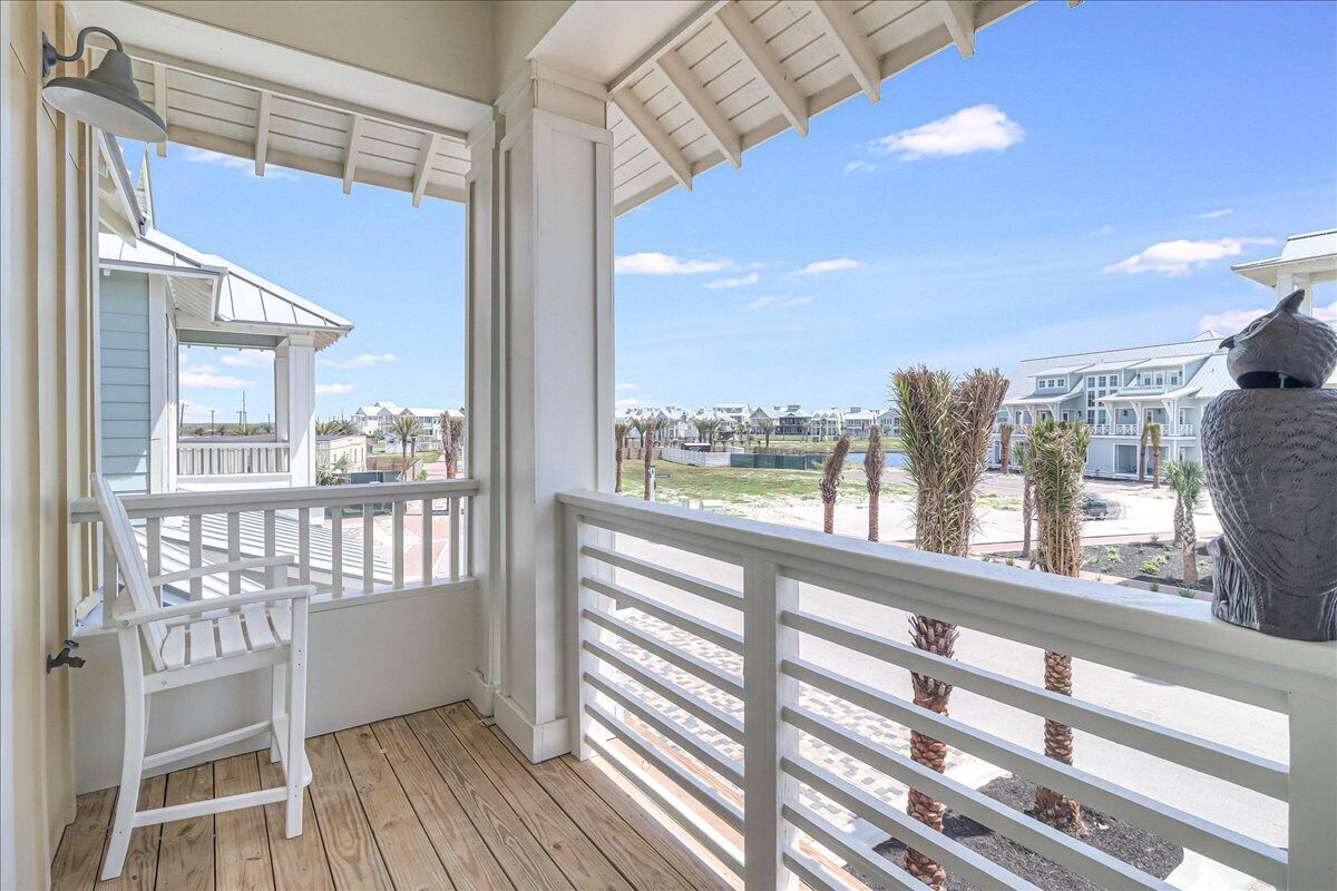 A wooden deck with a white railing, a white chair, and a decorative bird sculpture.