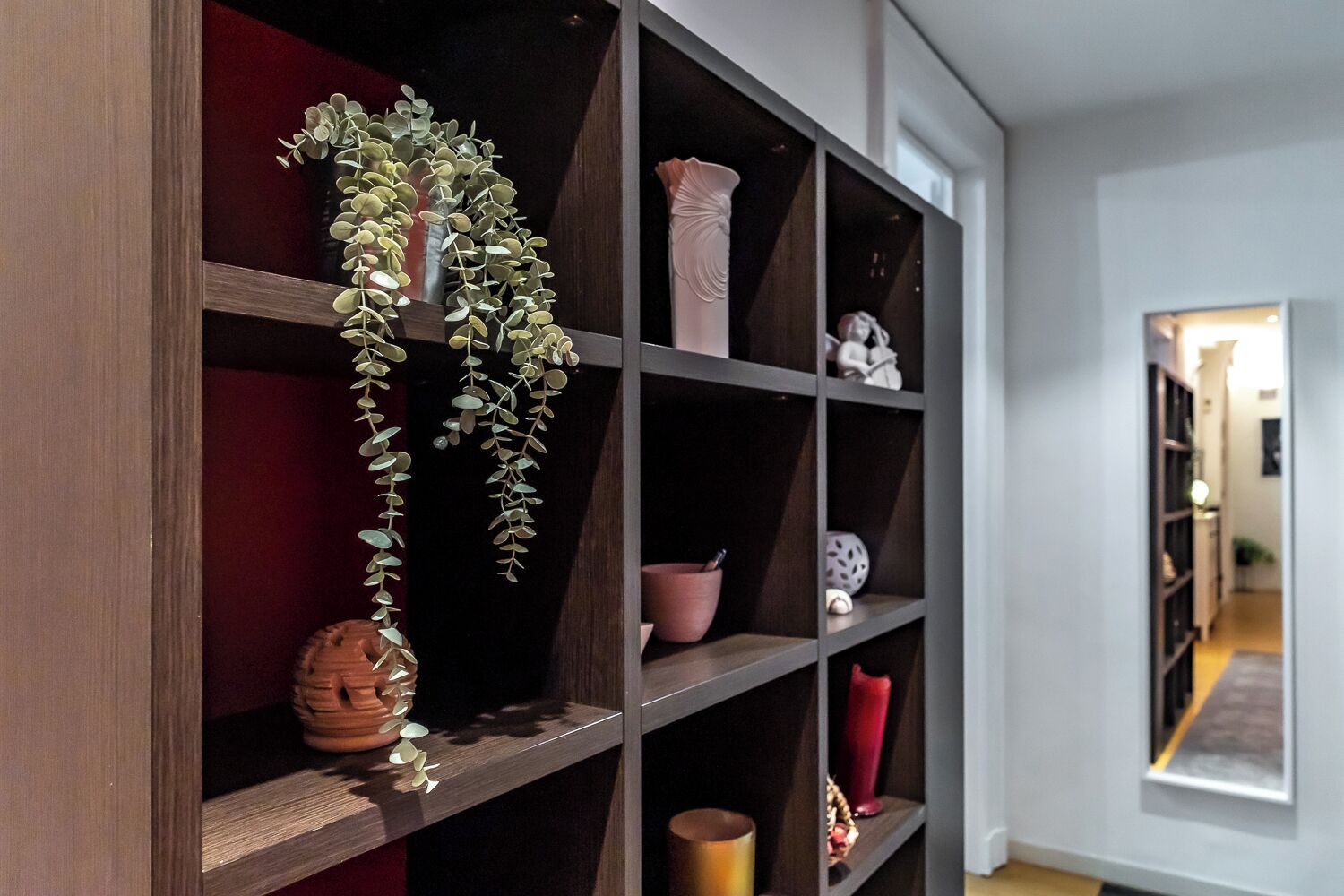A modern interior with a dark wood shelving unit displaying various decorative items.