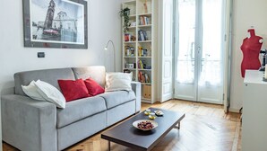 A living room with a grey sofa, a coffee table with a bowl of fruit, a bookshelf, and a framed picture on the wall. - Apple House al Duomo by Wonderful Italy (Turin)