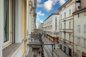 Une vue de rue avec des immeubles, un balcon et des piétons.