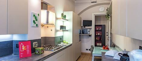 A modern kitchen with a gas stove, microwave, and a small dining area with a table and chairs.