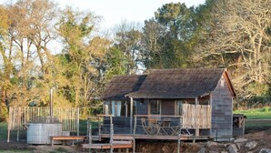 A wooden cabin with a dock extending into a calm lake, surrounded by trees.