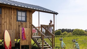 Eine Holzhütte mit Veranda, einem Surfbrett und Fahrrädern.