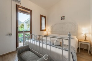 Une chambre à coucher avec un lit, des tables de chevet, une fenêtre et une vue sur la verdure.