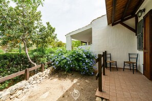 A patio area with a stone wall, a wooden fence, and a bench.