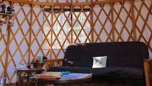 Interieur van een joert met een dakkoepel, een bank en een tafel met spullen erop.