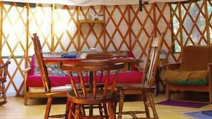 A yurt with a central table and chairs, surrounded by wooden benches and cushions. - "Mt. Brook Yurt" Off Grid Mountain Yurt (Denmark)