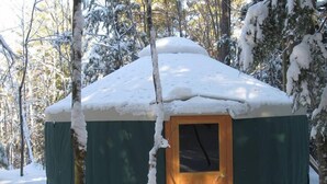 A snow-covered yurt with a wooden door and a small window, surrounded by trees and snow. - "Mt. Brook Yurt" Off Grid Mountain Yurt (Denmark)