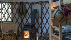 A cozy interior of a yurt with a wood-burning stove, a ladder, and a chair. - "Mt. Brook Yurt" Off Grid Mountain Yurt (Denmark)