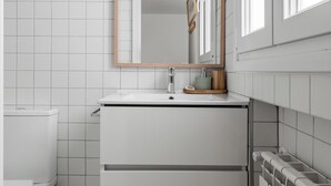 A modern bathroom with a white sink, a mirror, and a toilet. - Sol Studio II – In the City Center (Madrid)
