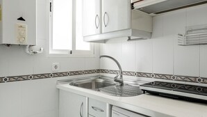 Una cocina con armarios blancos, un fregadero de acero inoxidable y un horno empotrado.