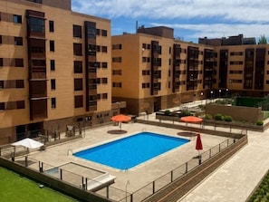 Un bâtiment moderne doté d’une piscine rectangulaire, d’un espace extérieur aménagé pour s’asseoir et d’une terrasse clôturée.