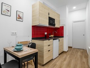 Compact kitchen with modern design, light cabinetry, and a dining area with table and chairs.