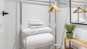 Et badeværelse med håndklædestige, spejl og en potteplante.